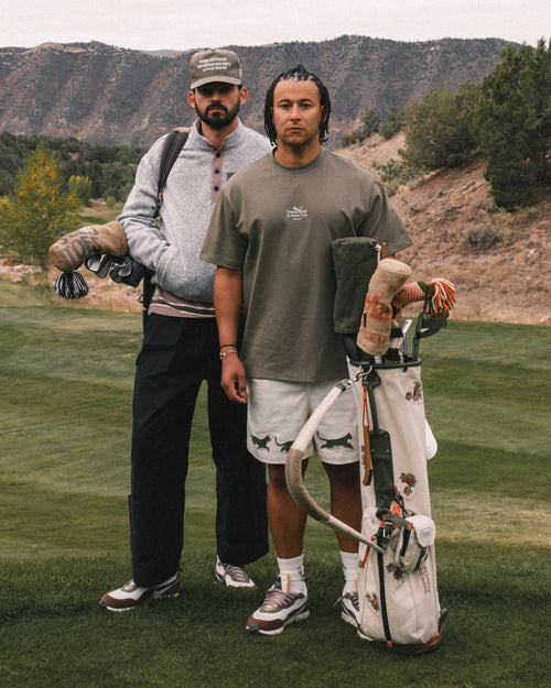 Two men standing on a golf course with golf bags