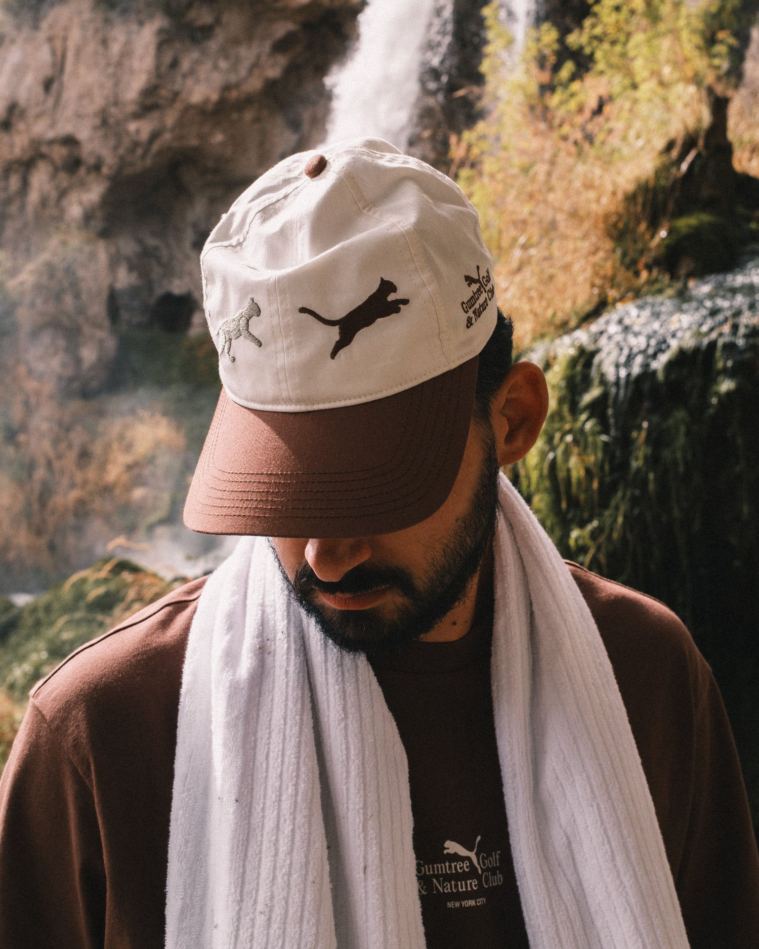 Man wearing a cap with animal designs in a natural setting