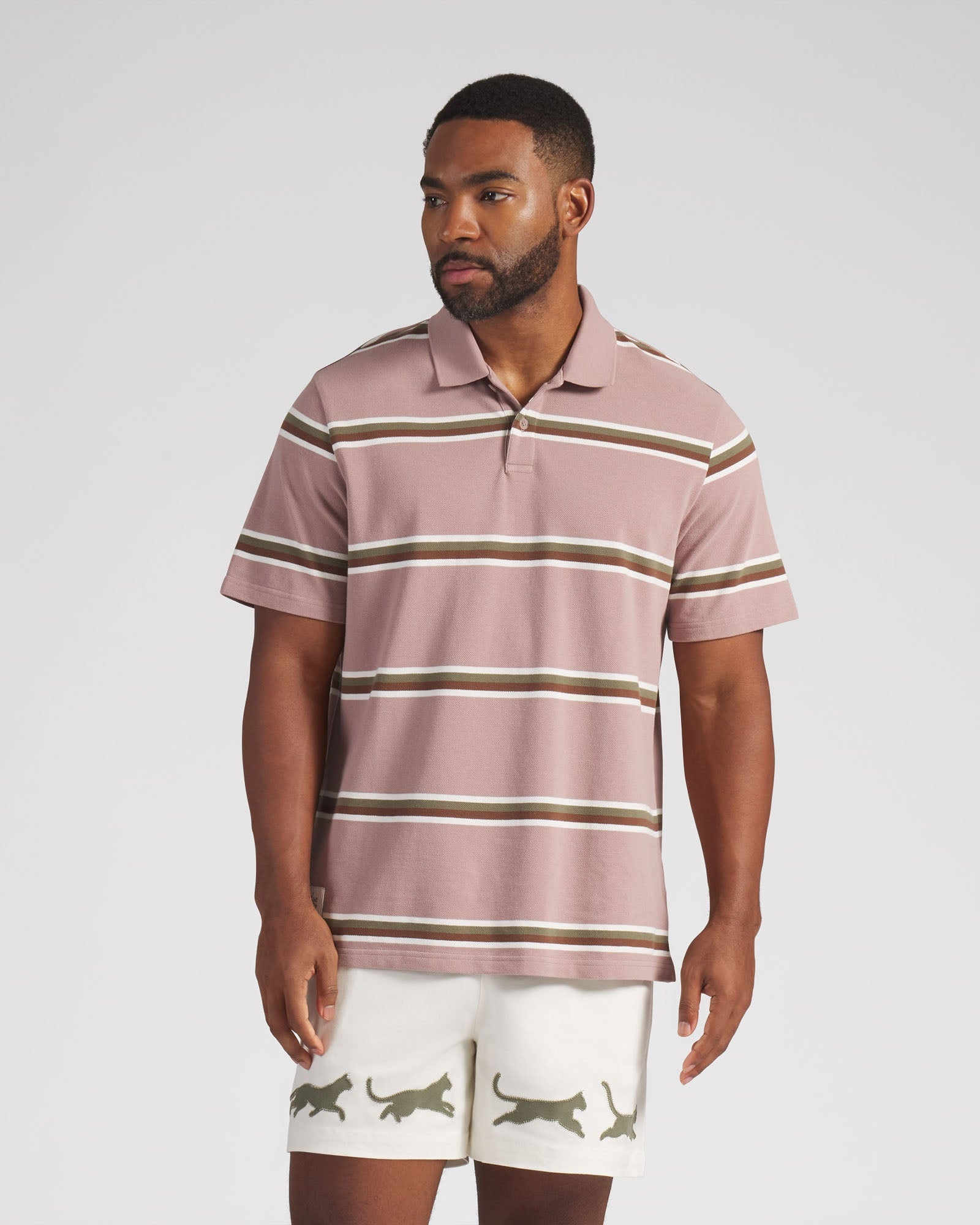Man wearing a striped polo shirt and shorts on a plain background