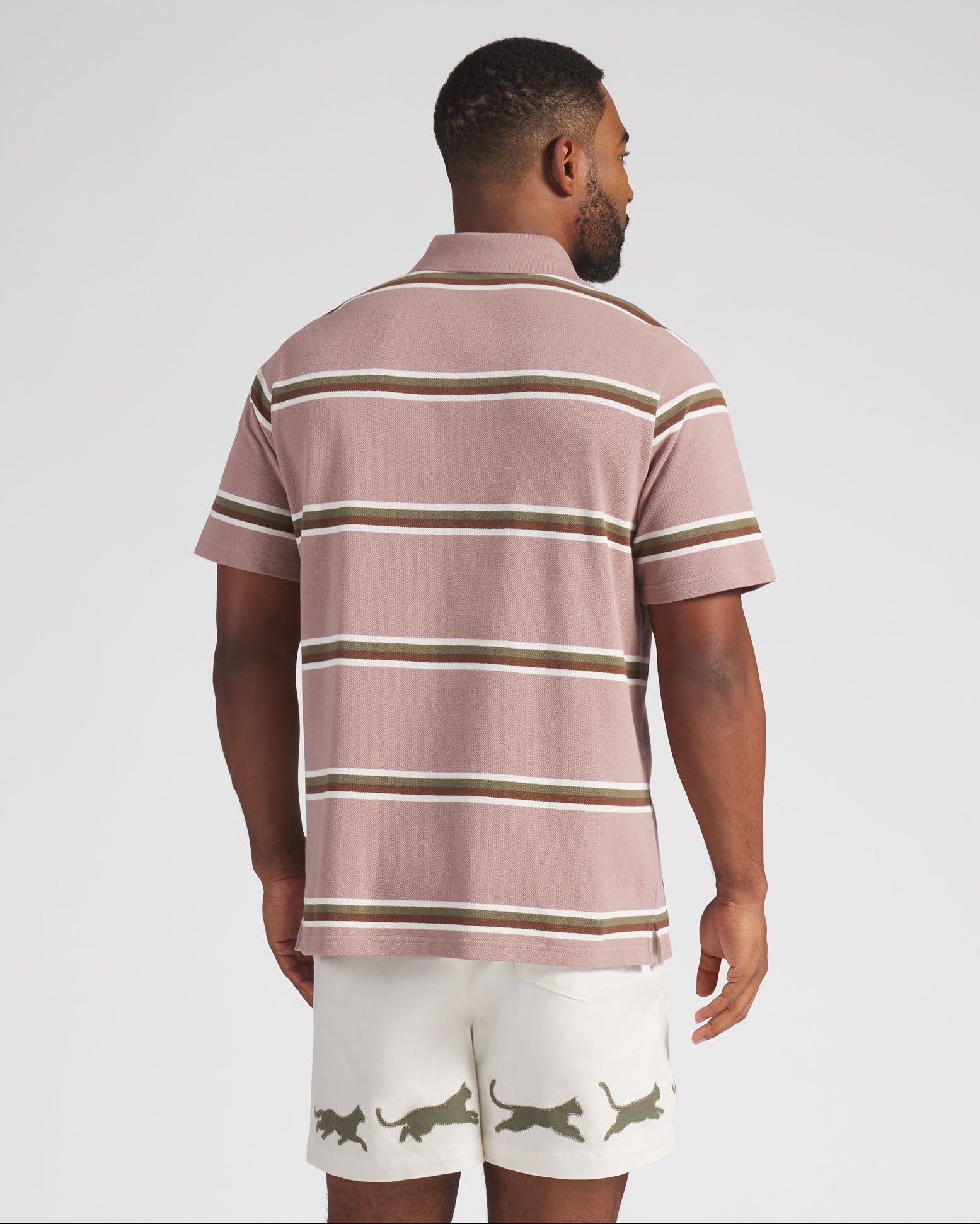 Man wearing a striped polo shirt and shorts on a plain background