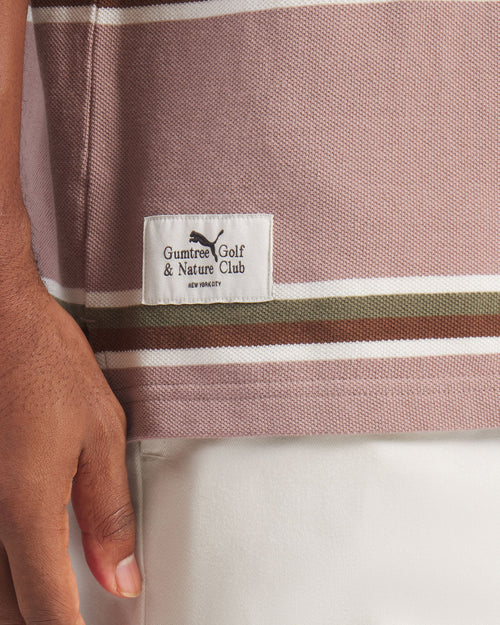 Close-up of a striped shirt with a Gumtree Golf & Nature Club label, held by a hand.