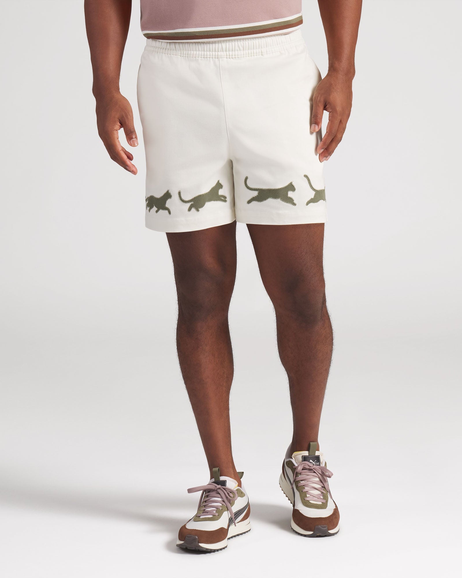 Person wearing white shorts with green cat prints on a plain background