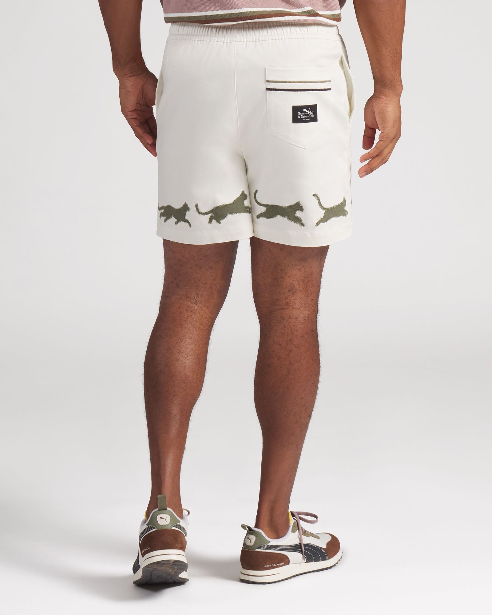 Person wearing white shorts with green animal prints on a plain background