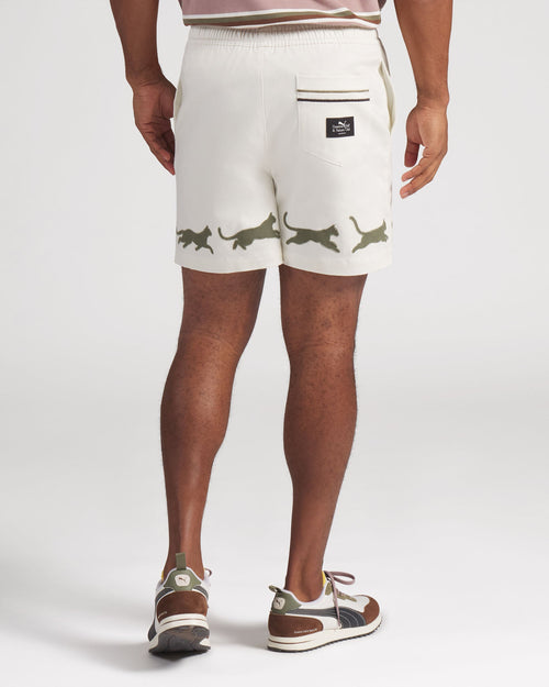 Person wearing white shorts with green animal prints on a plain background
