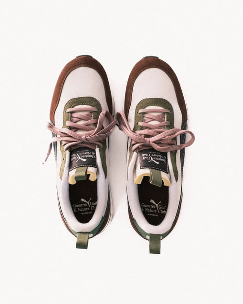 Pair of white sneakers with brown accents and pink laces on a white background