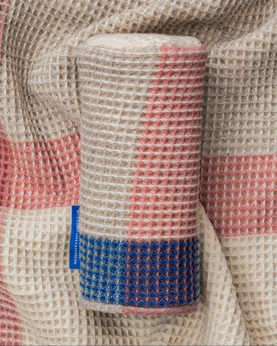Close-up of a textured fabric with a blue tag, featuring a checkered pattern.