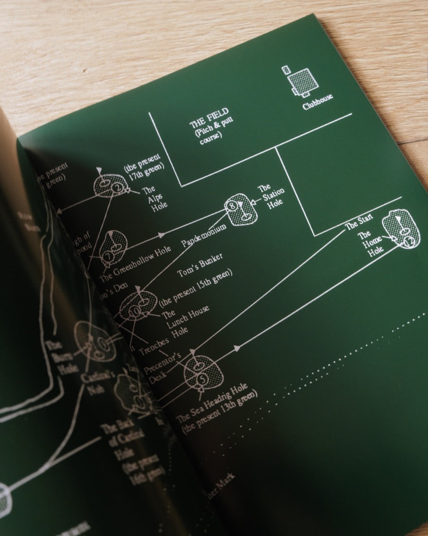 Green book with white line drawings on a wooden surface